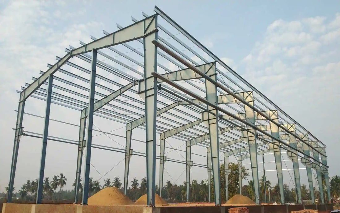 A steel shed frame standing on its plinth with roof purlins in place